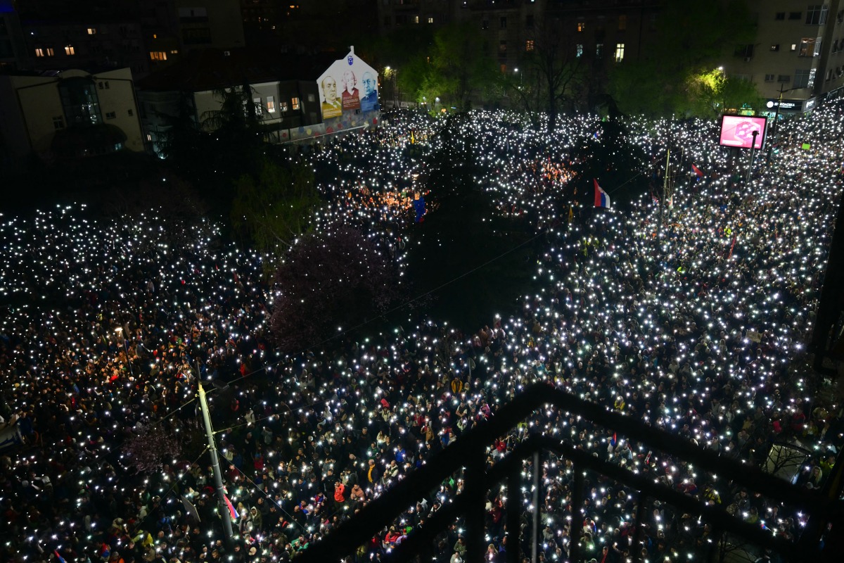 Thousands of protesters hold up their mobile phones to light up the night sky in memory of those who died in the Novi Sad roof disaster, as they take part in one of the largest anti-corruption demonstrations, in Belgrade on March 15, 2025. Photo by Andrej ISAKOVIC / AFP