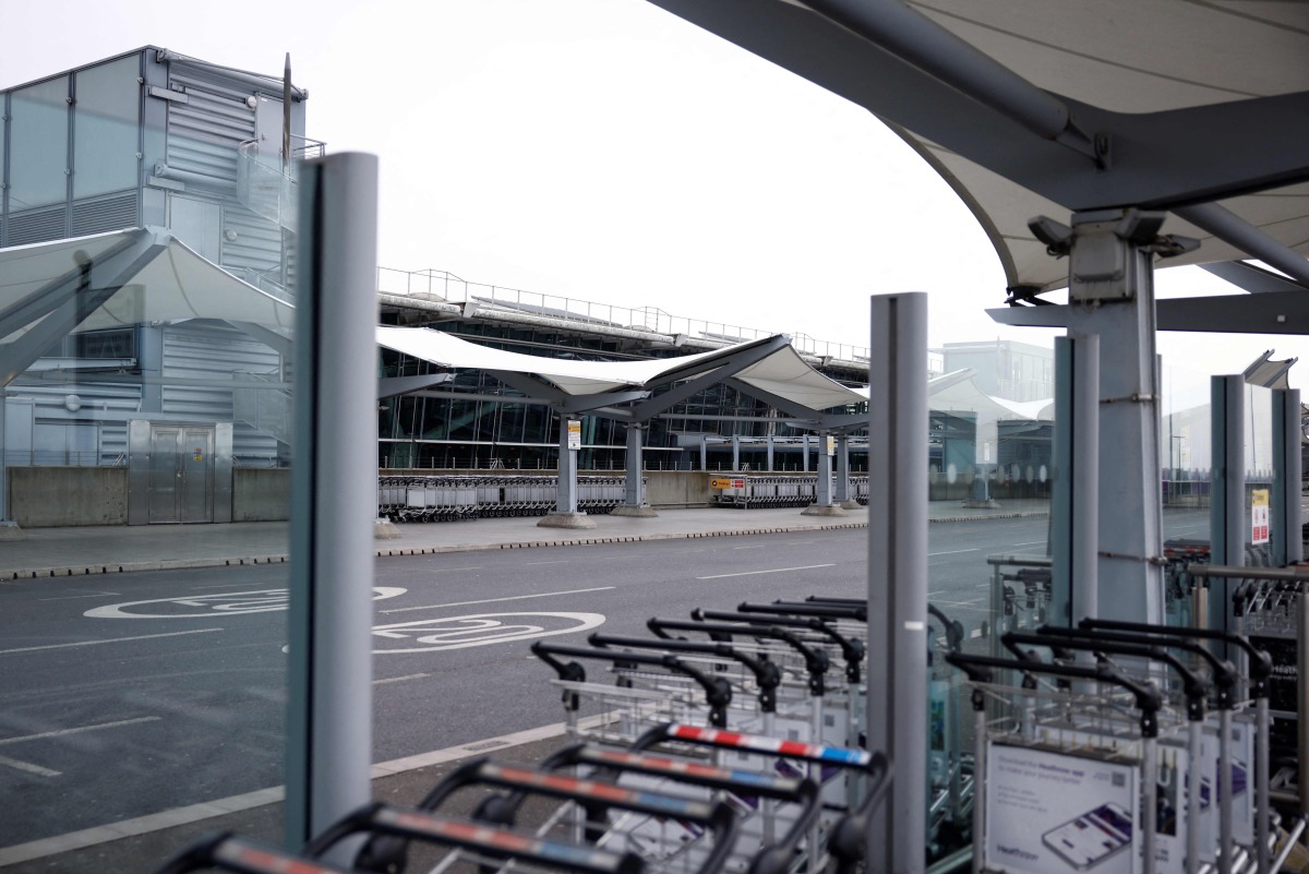 A photograph taken on March 21, 2025 shows trolleys lined up at the empty arrival area outside Terminal 5 of Heathrow airport following its closure after a fire broke out at a substation supplying power of the airport, in Hayes, west London. Photo by BENJAMIN CREMEL / AFP