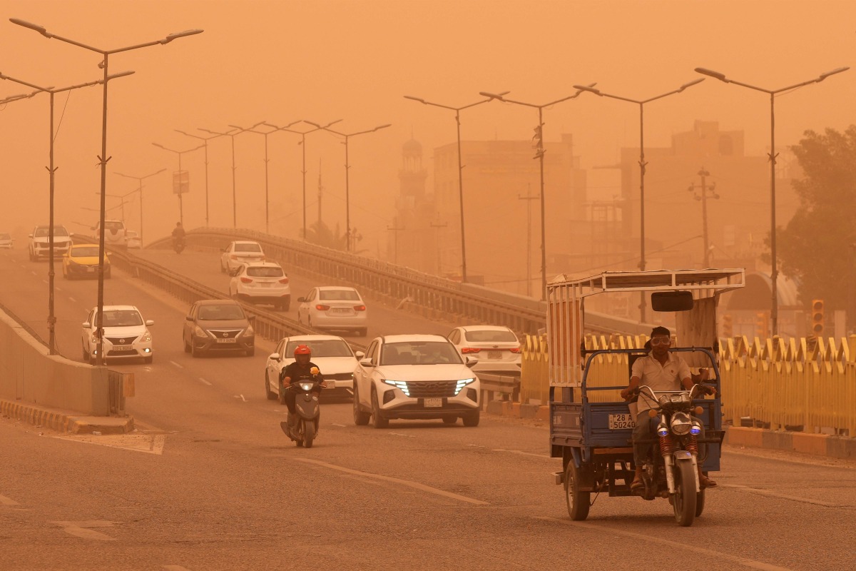 Motorists drive their vehicles along a highway through low visibility conditions as a massive dust storm advances on Iraq's central city of Najaf on April 14, 2025. (Photo by Qassem al-KAABI / AFP)